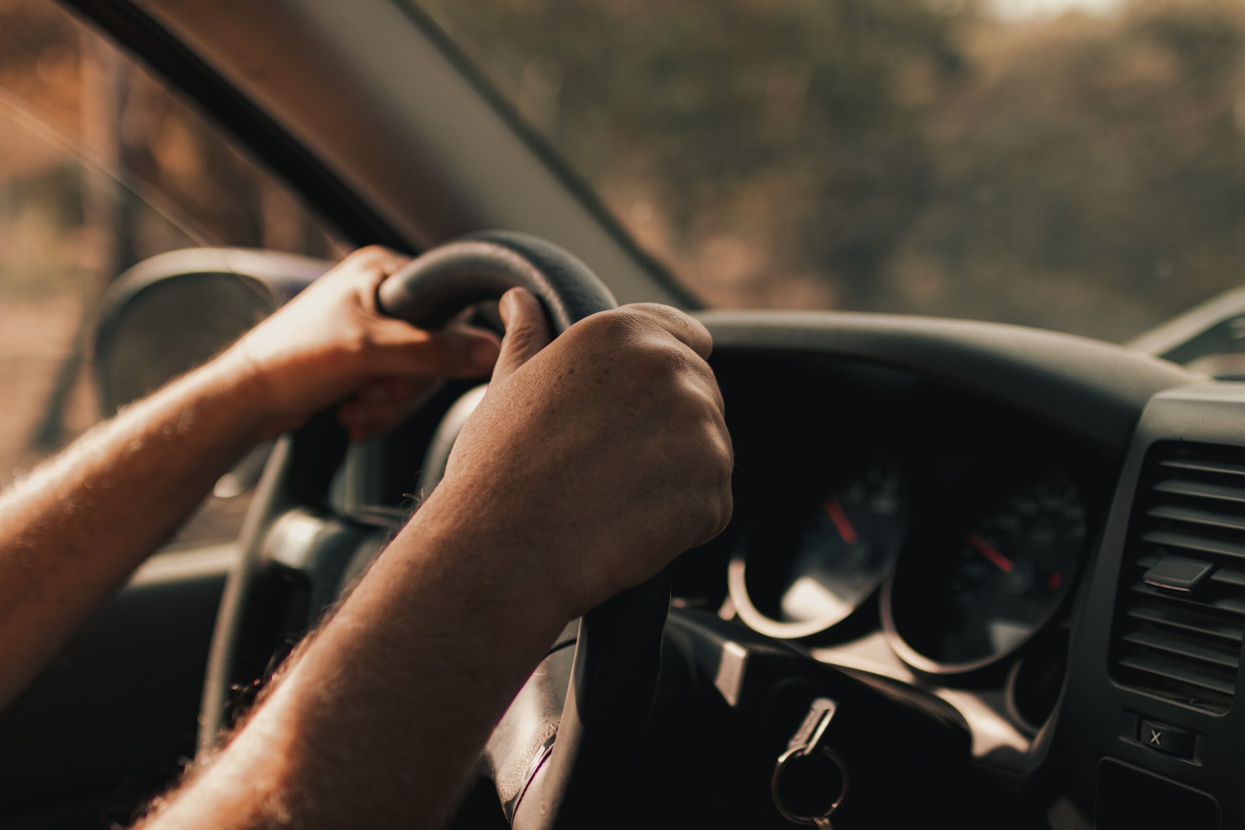 Driver holding the steering wheel while driving a car